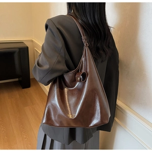Vue détaillée du sac cabas en cuir marron foncé avec nceud décoratif et fini brillant