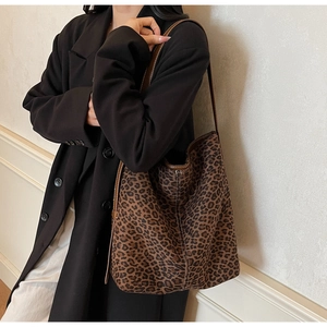 Detail of leopard print tote bag featuring brown trim and shoulder strap on model