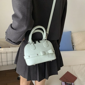 Close-up of mint green shell handbag with bow detail and adjustable shoulder strap