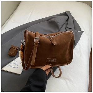 Detail der dunkelbraunen Wildleder-Schultertasche mit Holzperlenanhänger und Reißverschluss