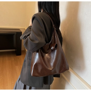 Vue détaillée du grand sac cabas marron foncé avec logo doré et texture en cuir lisse