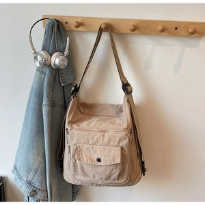 Detail of beige nylon tote bag with multi-pocket design and adjustable shoulder straps