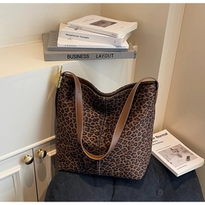 Close-up of leopard print tote bag featuring brown leather strap and gold hardware