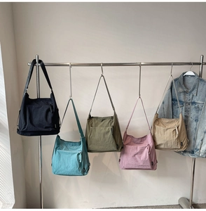 Detailed row of oversized nylon crossbody bags in five colors on a display rack