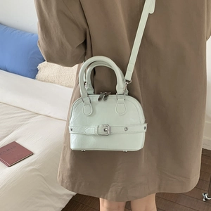 Detailed close-up of a mint green mini shell bag featuring dual zippers and silver metal rings