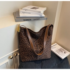 Detail of leopard print tote bag with brown leather straps and golden metal padlock charm