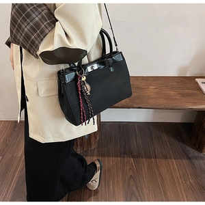 Detail view of black matte leather tote with silver twist lock and braided rope ornament