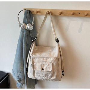Detail view of off-white multi-pocket messenger bag with adjustable strap and textured fabric