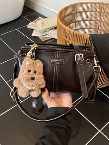 Sac à main en cuir noir brillant avec breloque en peluche marron et détails argentés