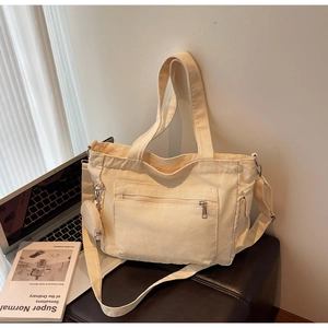 Close-up of cream canvas tote bag with round pouch on a leather bench for daily commute