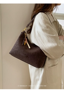 Detail of dark brown matte leather shoulder bag with decorative beaded tassel charm