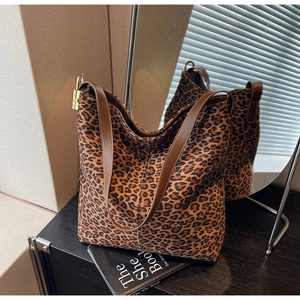 Detail view of large leopard print tote bag with brown leather strap and gold hardware