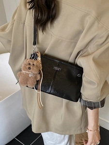 Sac à bandoulière en cuir noir rétro avec breloque d'ours en peluche en photo de rue