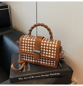 Detail of woven lattice handbag on book showing brown handle and silver clasp