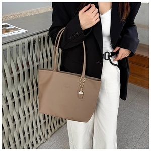 Detail of camel tote bag in premium pebble leather with gold chain pendant accent