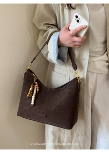 Close-up of vintage dark brown faux suede hobo bag with colorful beaded tassel detail