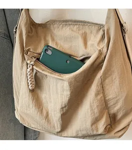 Detailed view of the front zipper pocket on khaki nylon crossbody bag for easy storage