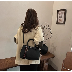 Chic black matte leather handbag with silver lock and silk scarf detail on shoulder