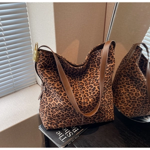 Detail view of large leopard print tote bag with brown straps and golden metal buckle