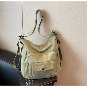 Detail of light green nylon crossbody bag showing multiple zip pockets and textured fabric