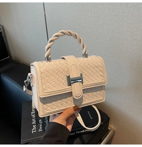 Detail of cream woven square handbag with twisted handle and silver metallic buckle