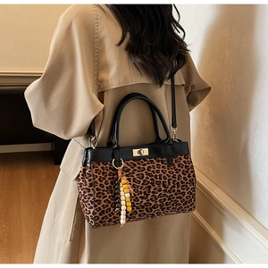 Dettaglio della borsa leopardata con finiture in pelle nera e chiusura girevole dorata