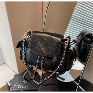 Détail du sac matelassé noir avec bandoulière chaîne, poches latérales et cuir ciré brillant