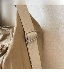 Close-up of adjustable shoulder strap with silver metal buckle on khaki canvas bag