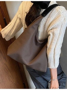 Grand sac à bandoulière marron en toile avec sangle noire porté par un mannequin