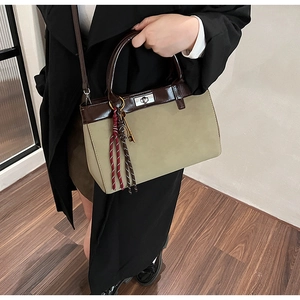 Detail view of Maillard style contrast handbag with tassel charm and silver twist lock