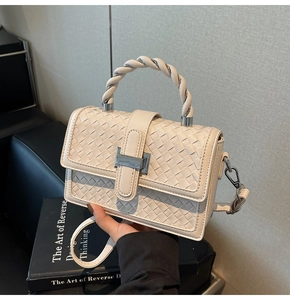 Detail of woven texture handbag with twisted handle and rectangular metal clasp