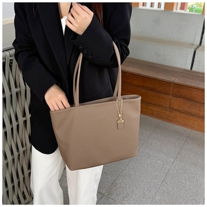 Deep khaki tote bag with pebbled leather texture and gold chain detail on model