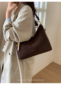 Detail of retro brown suede bucket bag featuring elegant wooden bead tassel and bronze hardware