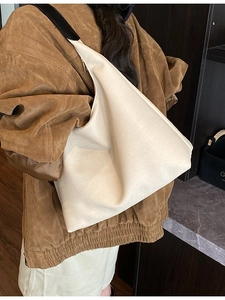 Sac fourre-tout beige nacré minimaliste avec bandoulière noire porté à l'épaule