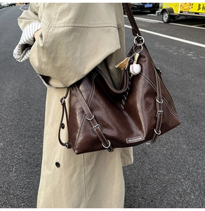 Detail of dark brown tote bag with contrast stitching and metallic buckle accents