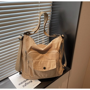 Detail of khaki nylon multi-pocket tote bag with adjustable strap in a casual setting