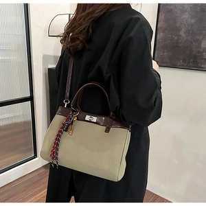 Detail of olive green vintage handbag with brown leather trim and silver metal twist lock