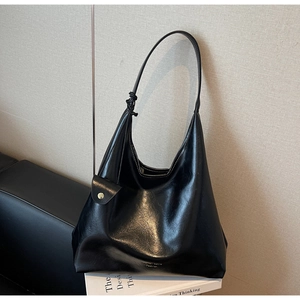 Détail du sac cabas noir brillant avec large bandoulière et fermoir doré chic