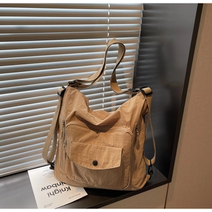 Detailed close-up of beige nylon crossbody bag with multi-pocket design and strap detail