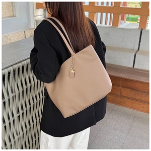 Detail of khaki leather tote bag with lychee texture and gold metal chain tag decoration
