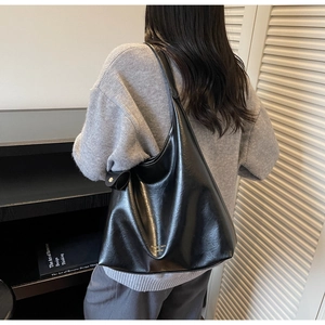 Gros plan du sac cabas rétro noir avec large bandoulière et détail noué sur le modèle
