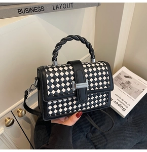 Detailed close-up of woven checkerboard handbag with twisted handle and metal buckle