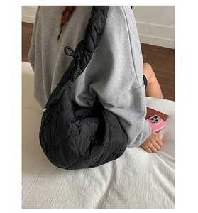 Détail du sac à bandoulière noir matelassé avec surpiqûres en cœur et large sangle