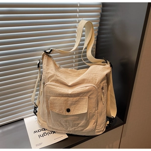 Macro shot of off-white tote bag showing crinkled texture, front flap pocket and zippers