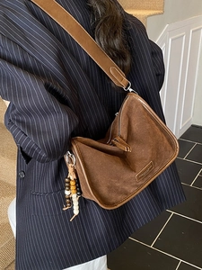 Braune Retro-Umhängetasche aus Wildleder mit breitem Gurt und Quasten-Detail am Modell