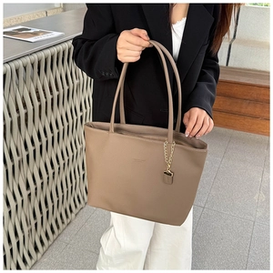 Macro detail of taupe lychee texture leather tote bag with elegant gold chain charm