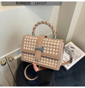 Close-up of woven checkerboard pattern leather handbag with twisted handle and silver clasp