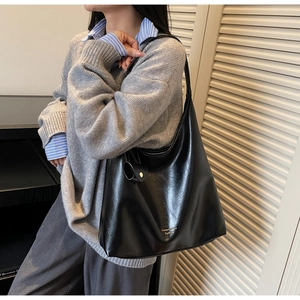 Détail d'un sac à épaule noir minimaliste en similicuir avec logo doré et pendentif décoratif