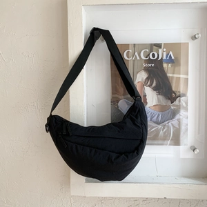 Close-up of a black nylon crescent crossbody bag with adjustable strap and metal zipper