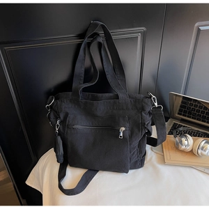 Close-up of black canvas tote bag featuring an outer zipper pocket and round coin purse